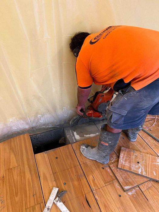 Hand saw cutting a floor opening behind dust screens