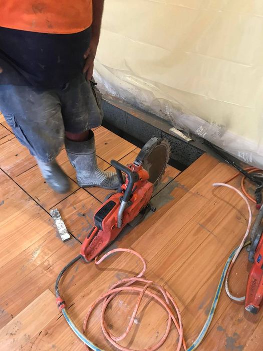 Hand saw finishing cuts through a timber-finished floor