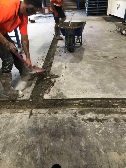 Crew clearing a service trench in a warehouse slab