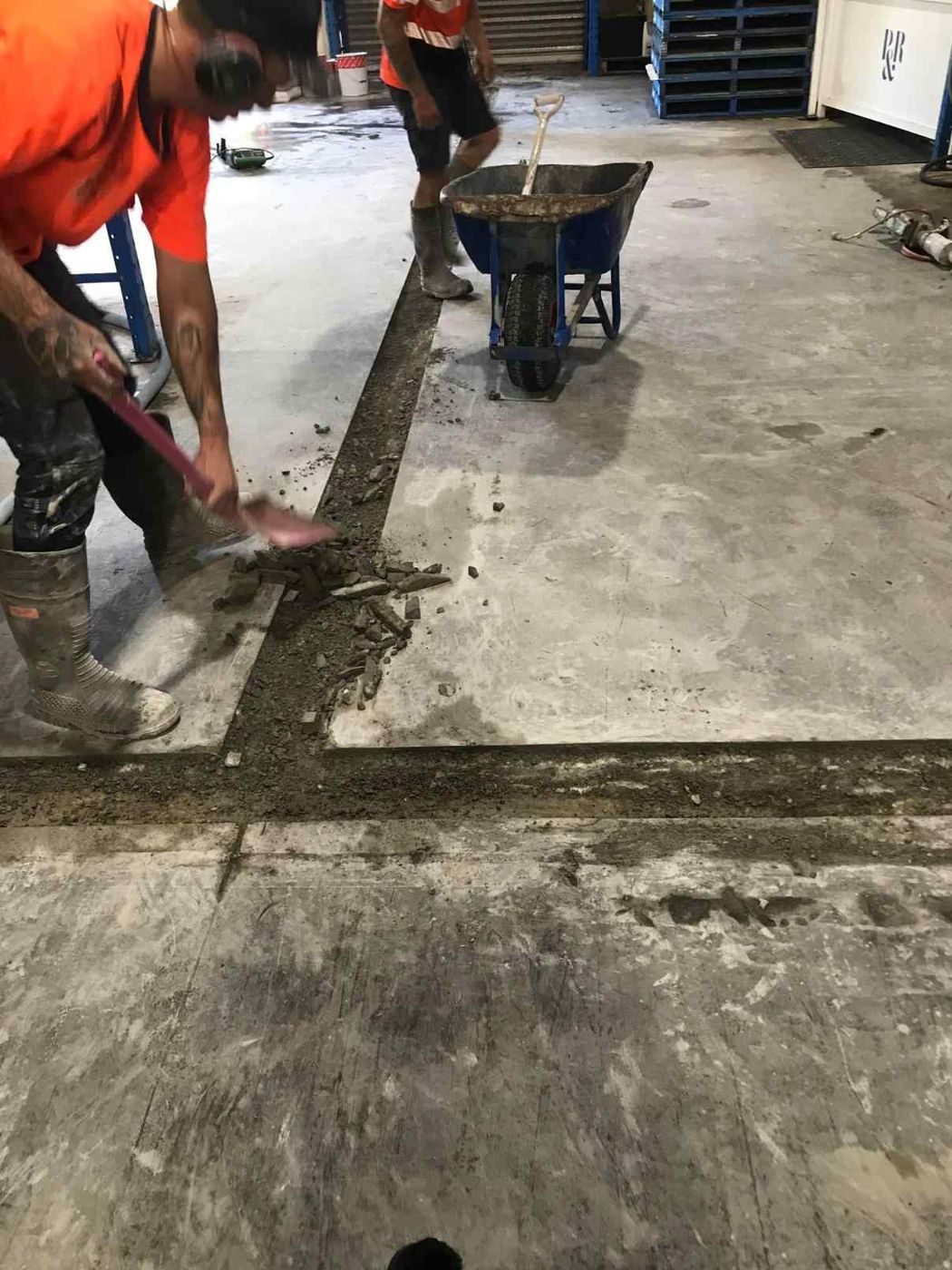 Crew clearing a service trench in a warehouse slab